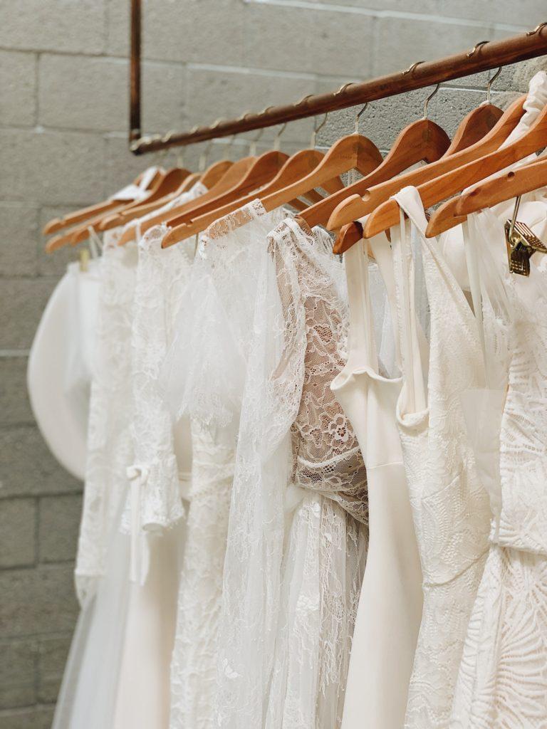 Beautiful wedding gowns arranged on wood hangers in an elegant bridal shop